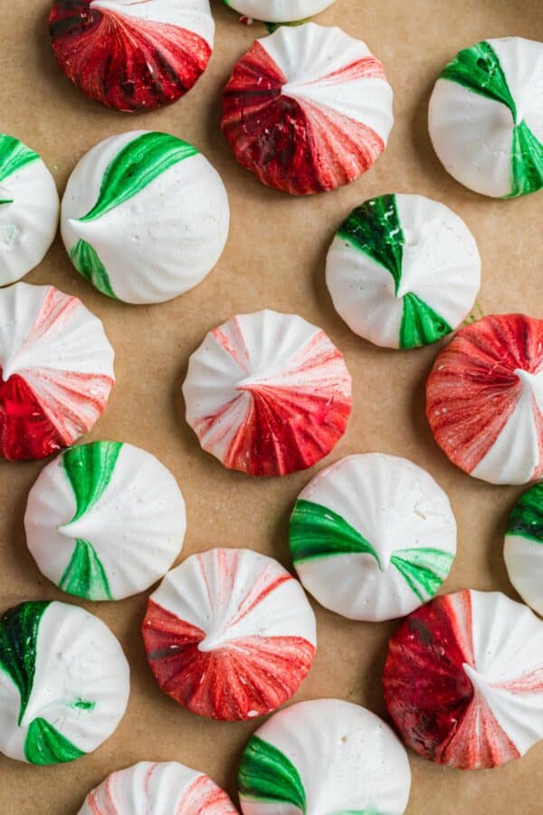 Parchment paper with red and green meringue cookies.