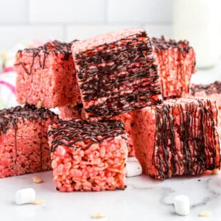 Cherry krispie treats with chocolate stacked on counter.