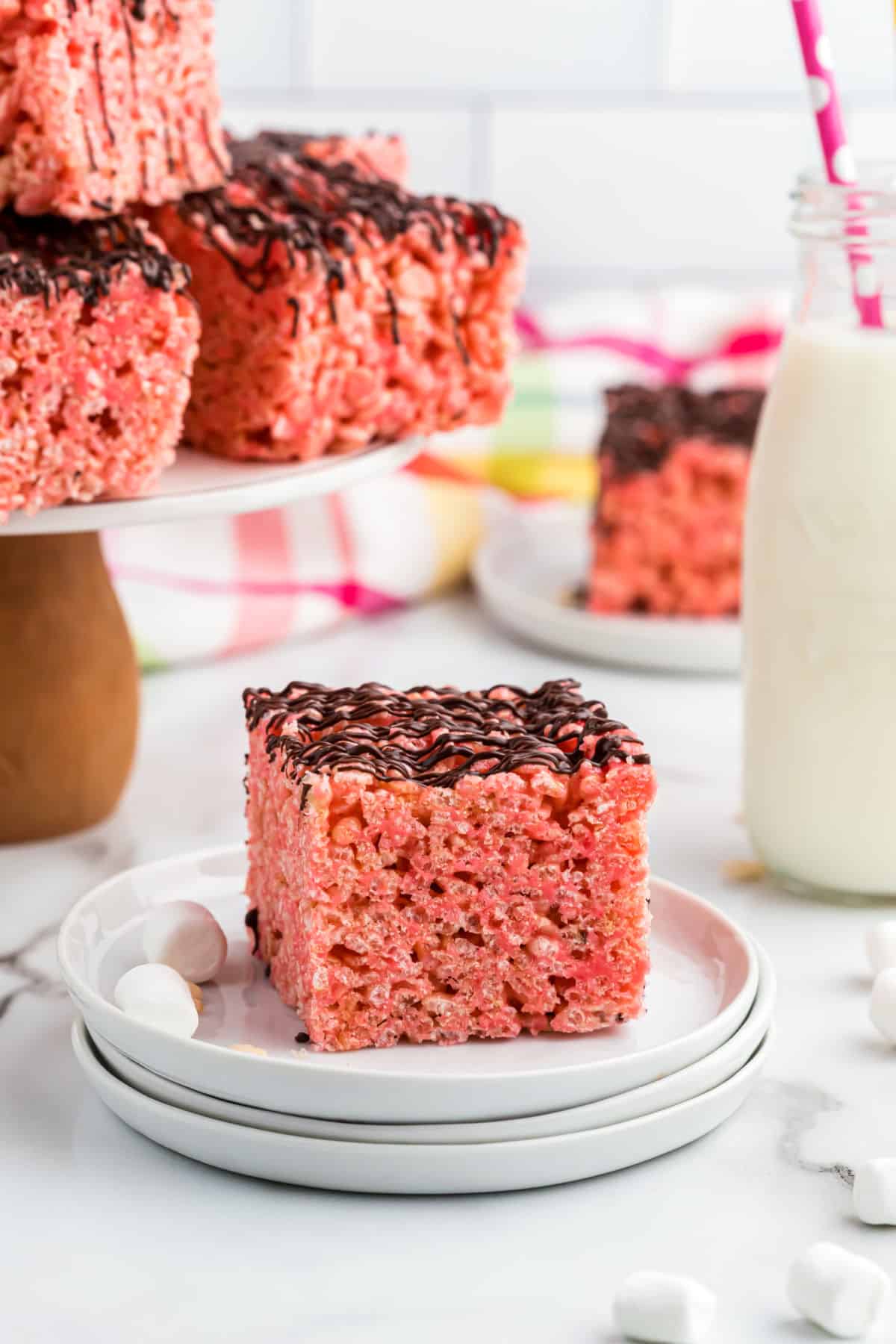 Cherry rice krispie treats cut into squares and drizzled with chocolate.