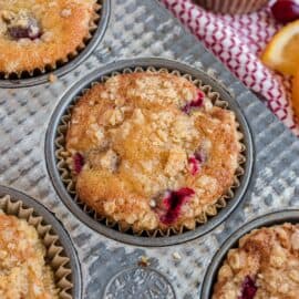 Cranberry orange muffins in a muffin pan with streusel.