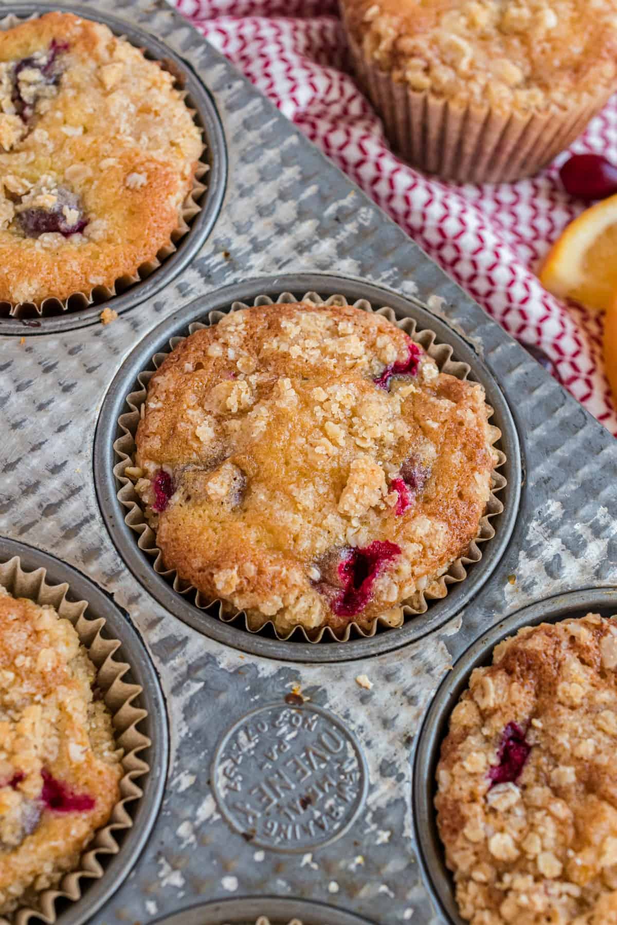 Cranberry orange muffins in a muffin pan with streusel.