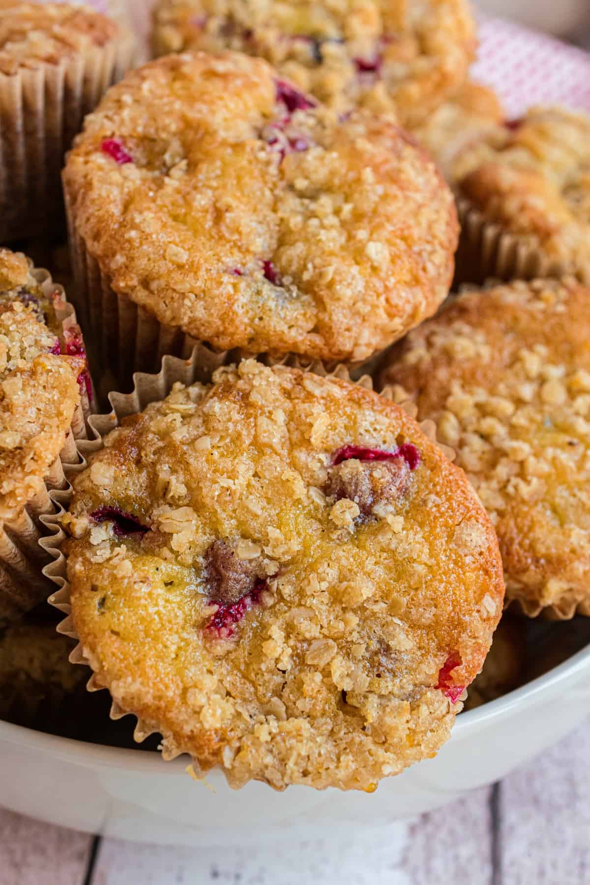 Streusel topped cranberry muffins in a white bowl.