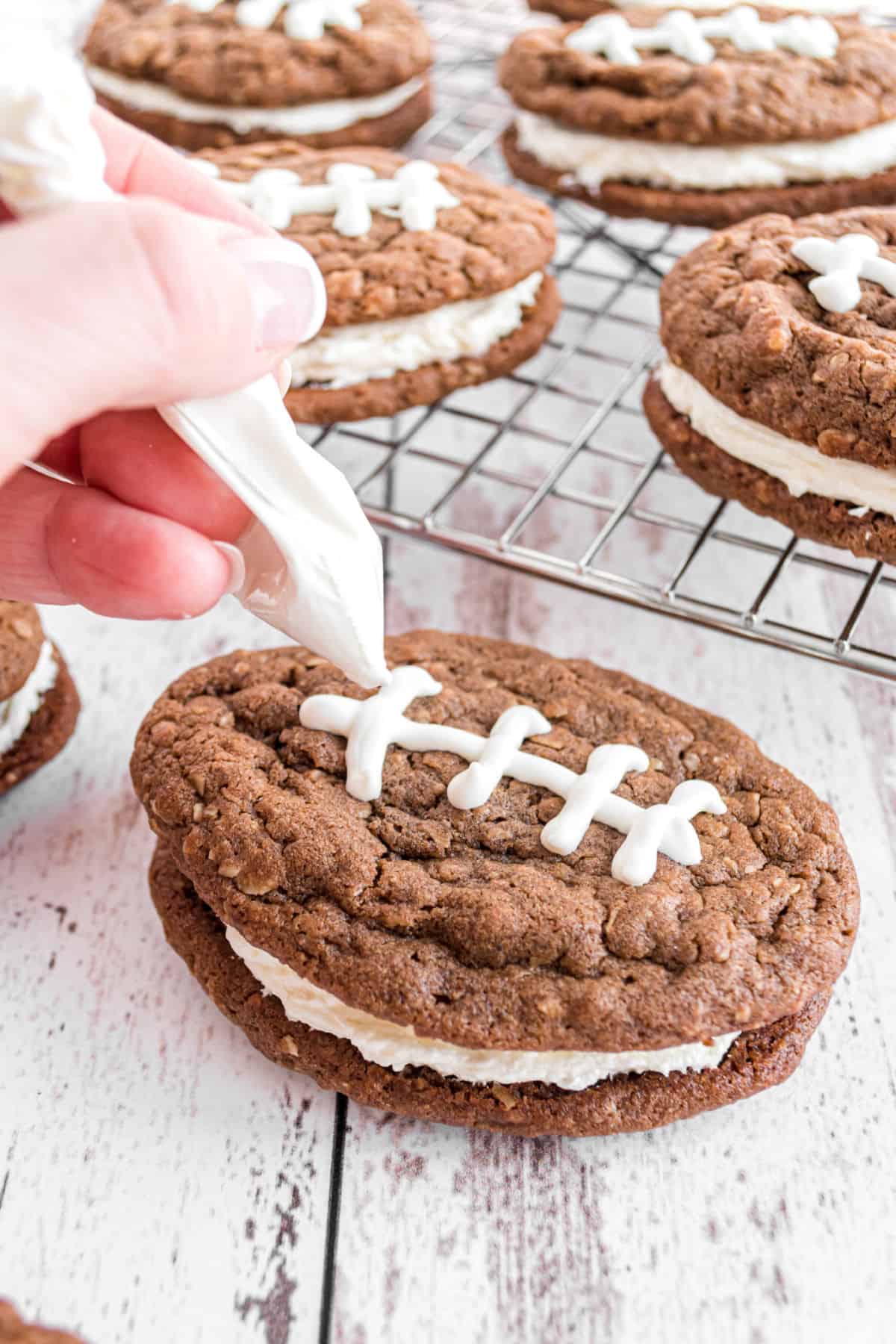 White chocolate in a ziploc bag being piped onto oatmeal cream pie footballs.