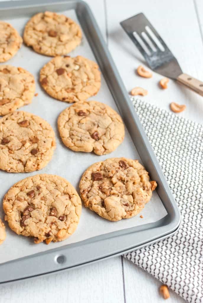 Cookies on a baking sheet with cashews.