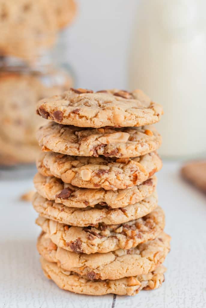 Tall stack of toffee cashew cookies on a wooden surface.