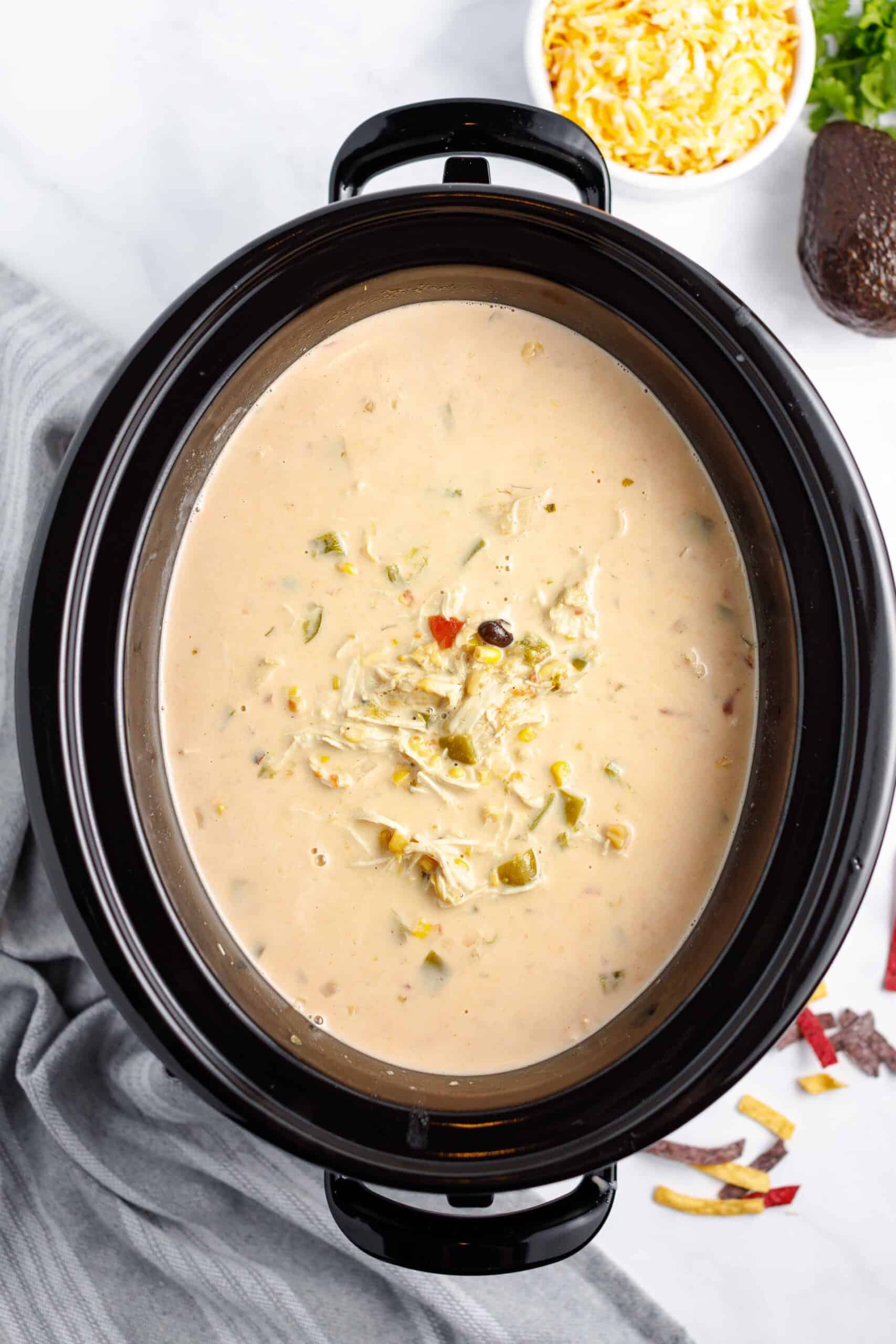 Slow Cooker Turkey Taco Soup with toppings: cheese, avocado, and tortilla strips.