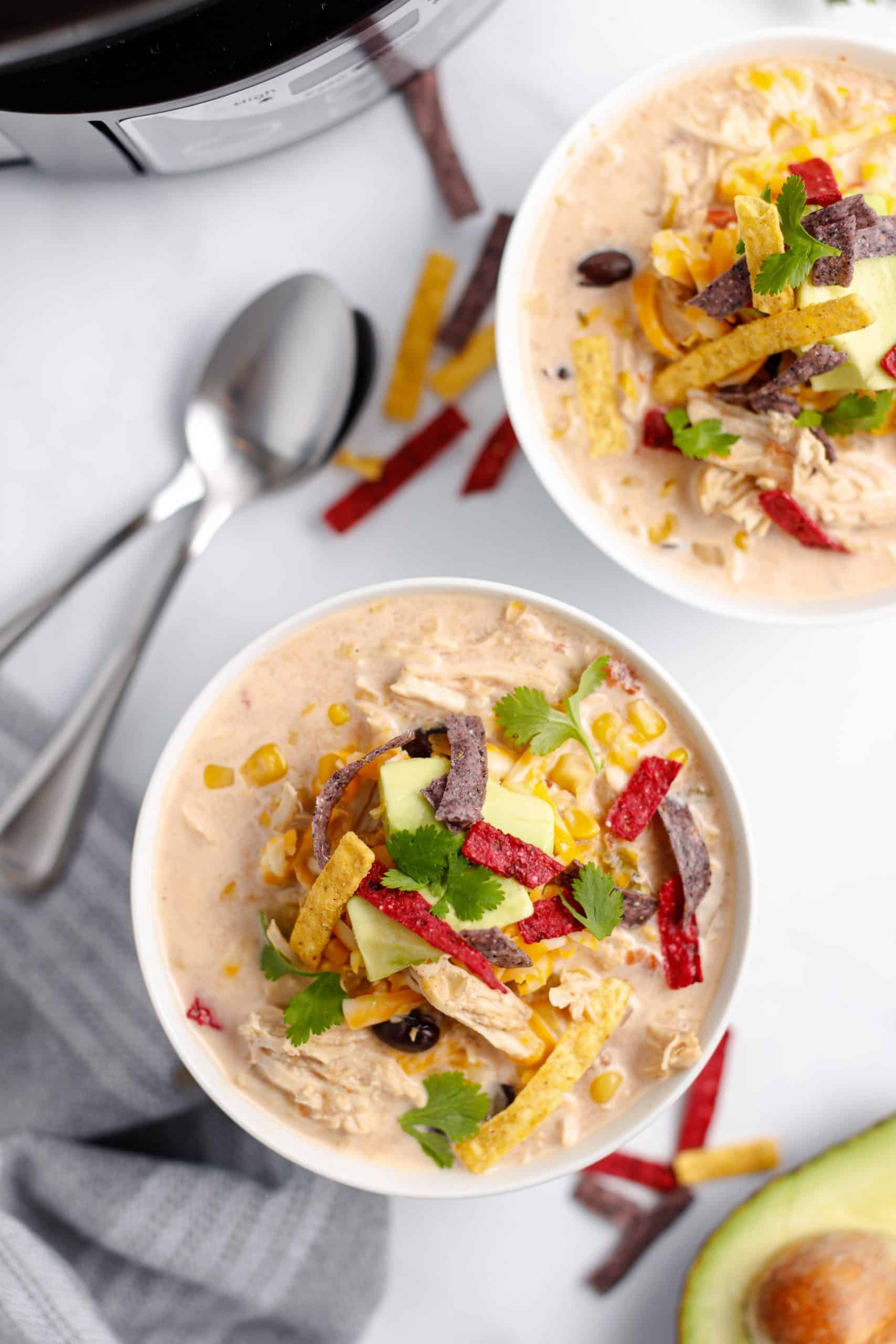 Two bowls of turkey taco soup topped with cheese, avocado, tortilla strips. Taco Soup made in the slow cooker or crockpot.