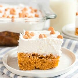 Slice of butterscotch cake on a white dessert plate, and light blue striped linen napkin.