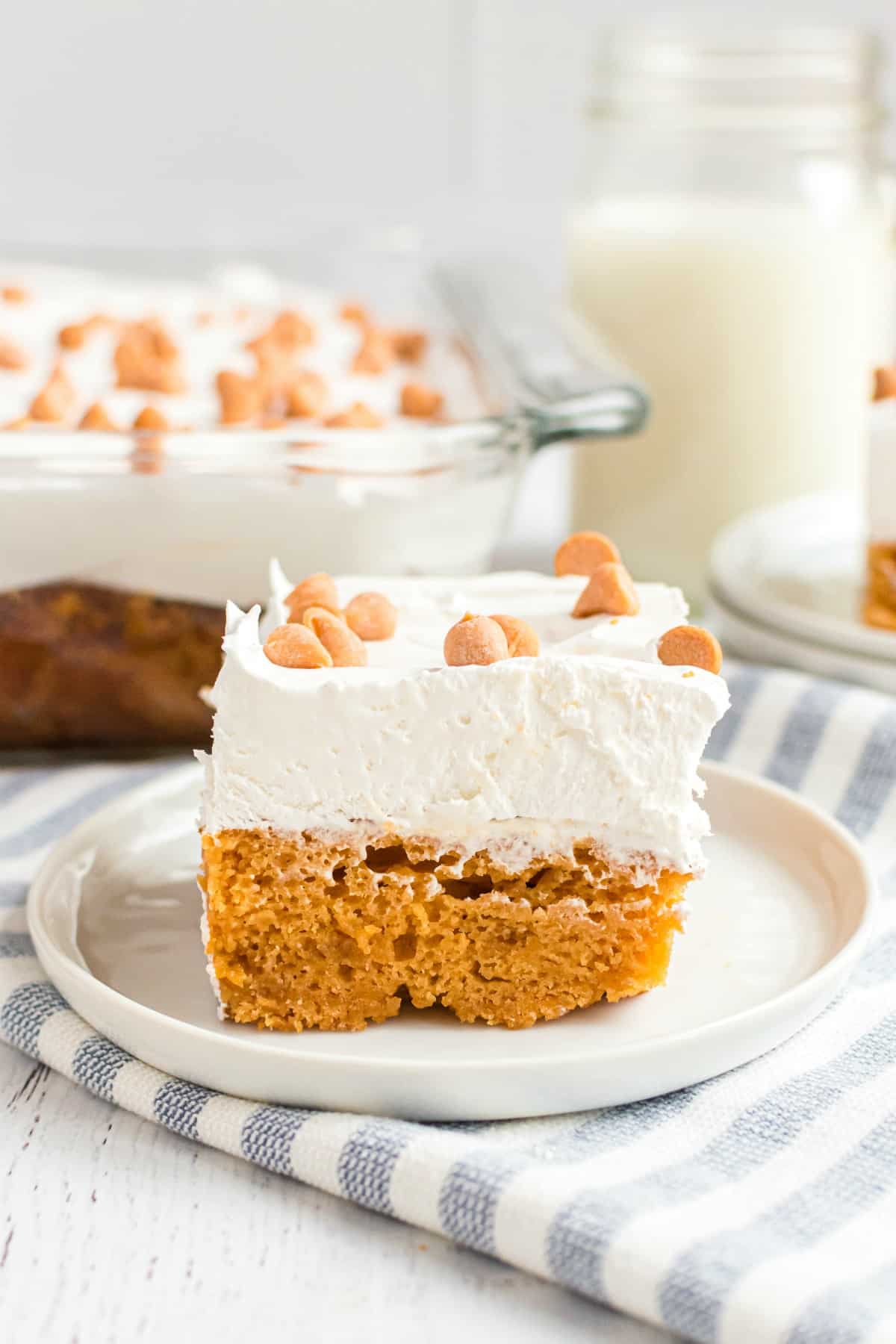 Slice of butterscotch cake on a white dessert plate, and light blue striped linen napkin.