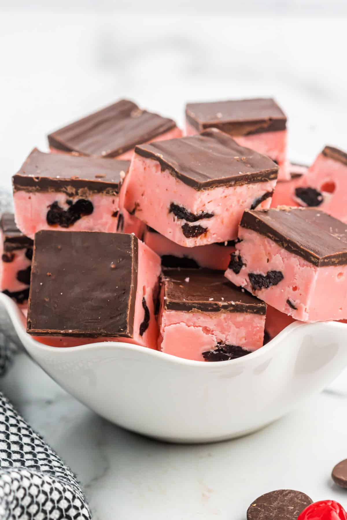 Cherry fudge cut into squares and served in a scalloped white bowl.