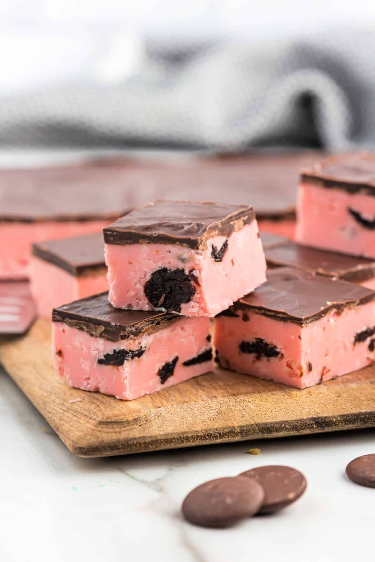 Cherry fudge topped with dark chocolate on wooden board.