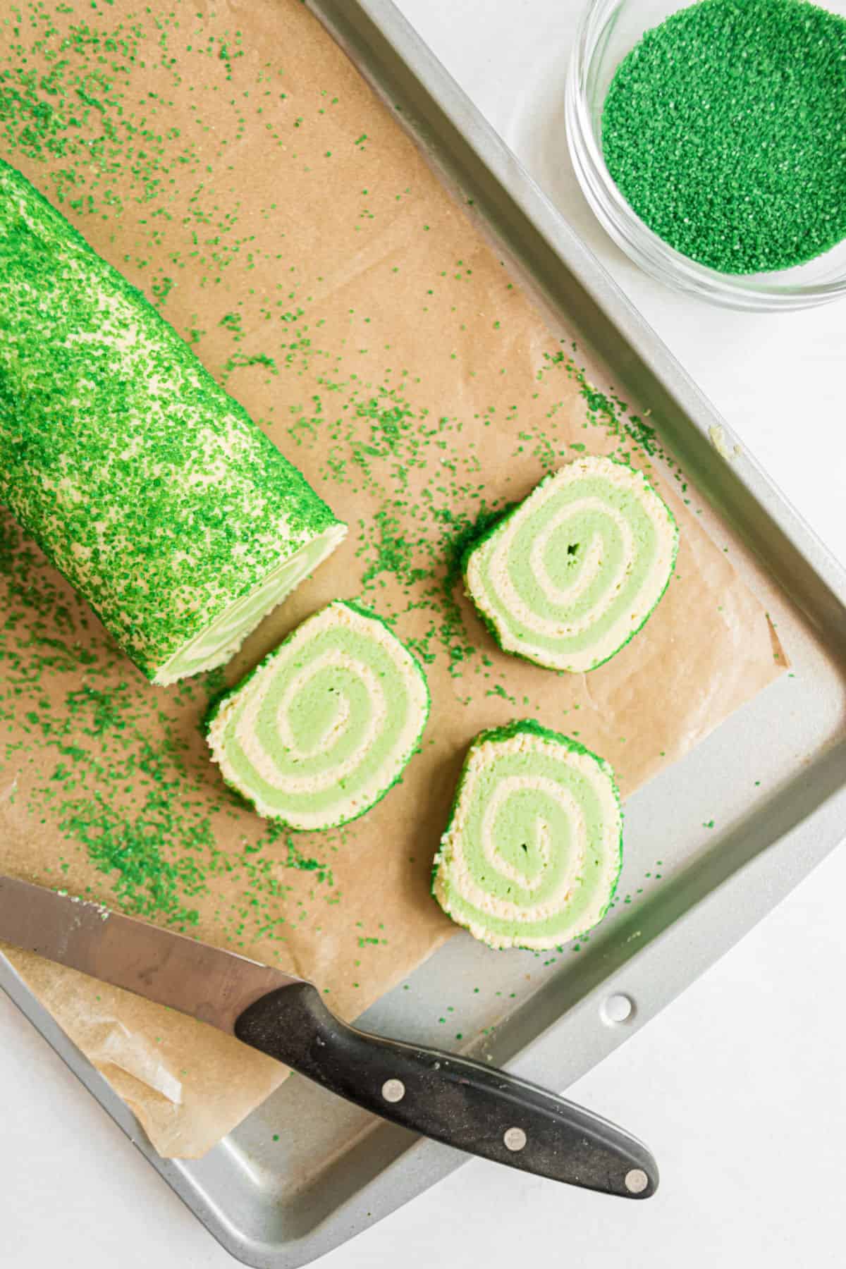 Slices of icebox cookies with lime swirls on parchment paper.