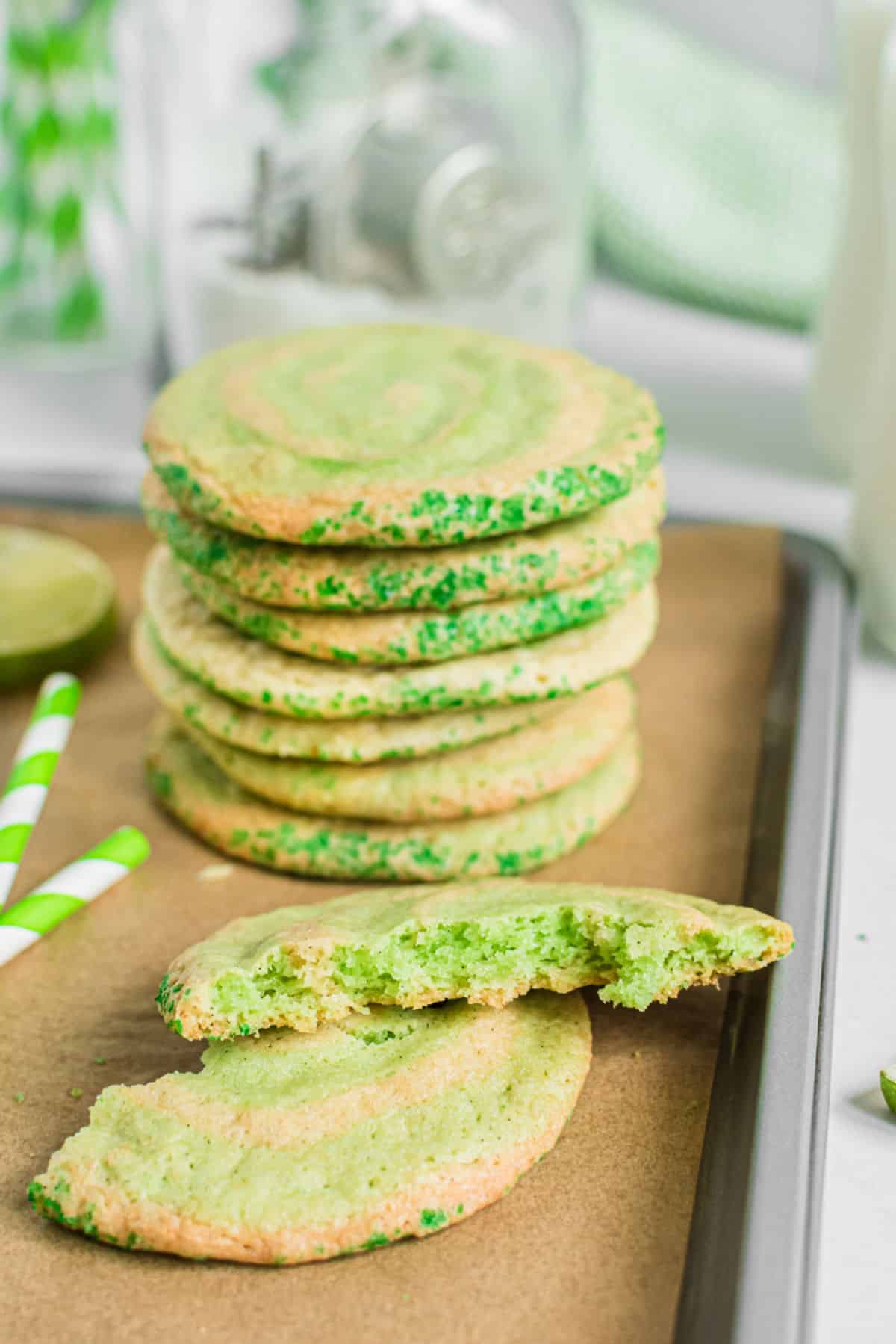 Stack of lime swirled icebox cookies on cookie sheet with one cookie broken in half.