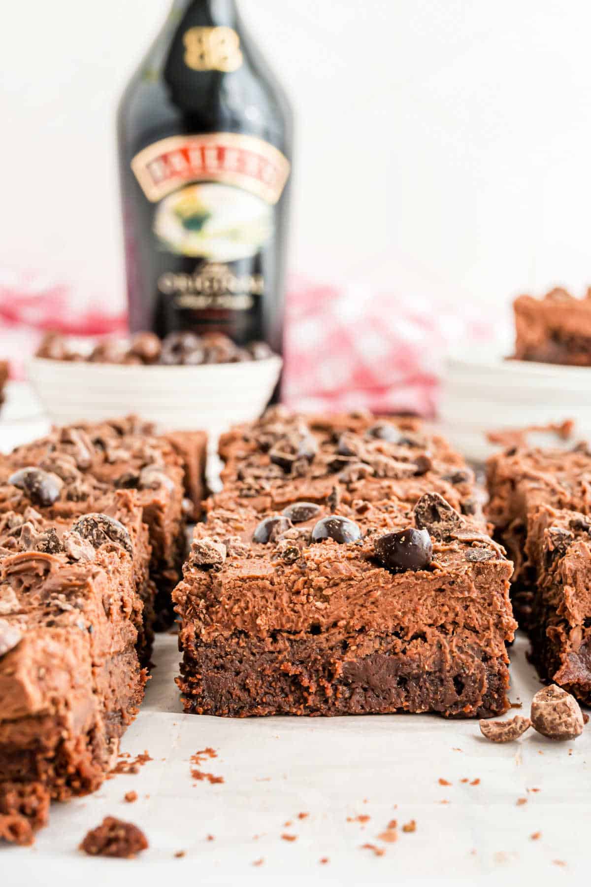 Brownies with frosting and espresso beans and a bottle of Bailey's in background.