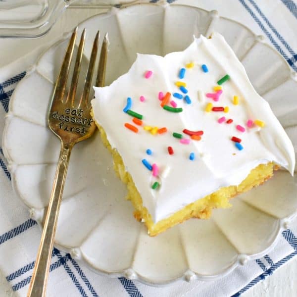 Slice of lemon cake made with pudding and topped with whipped cream.