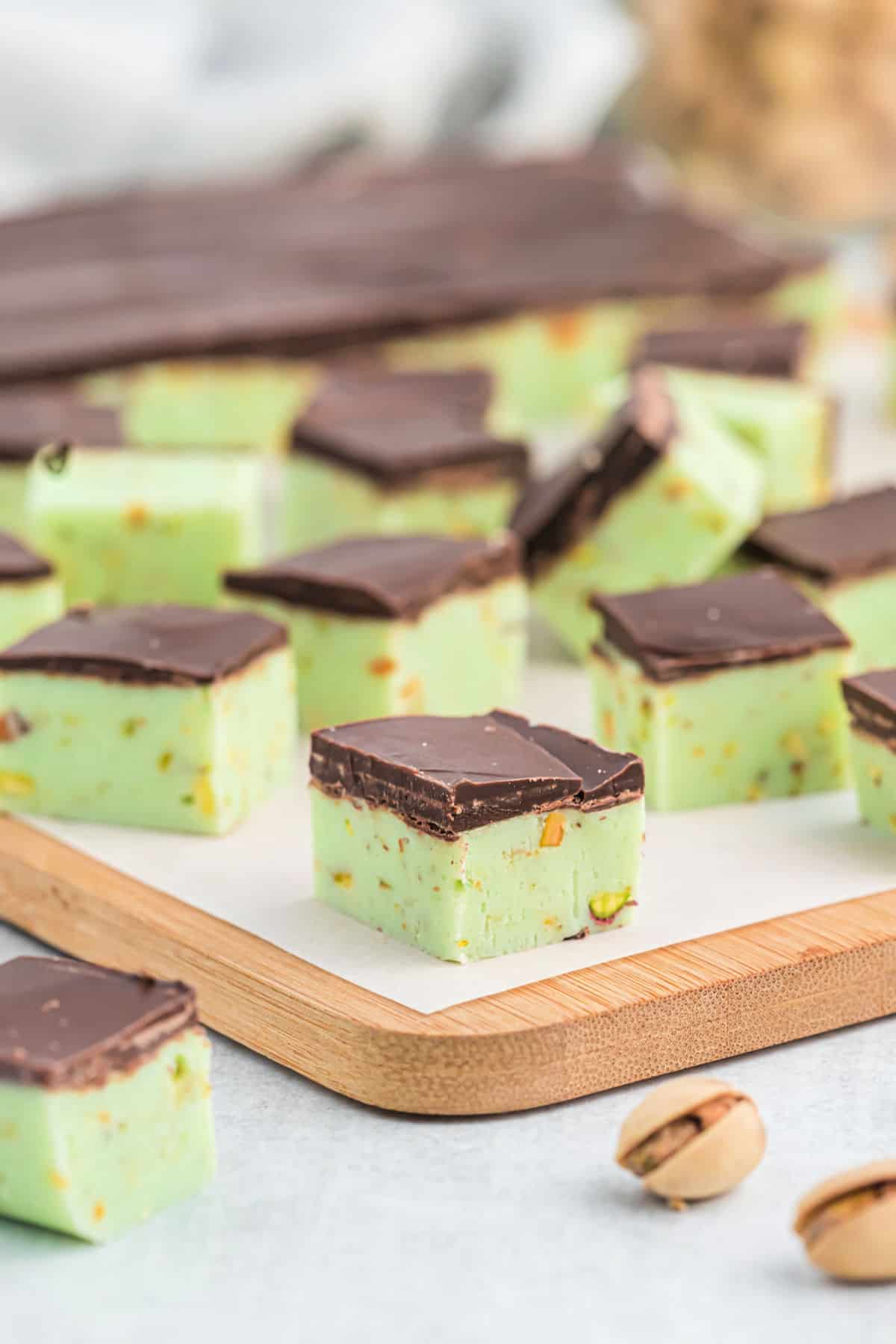 Pieces of pistachio fudge cut into squares on a cutting board.