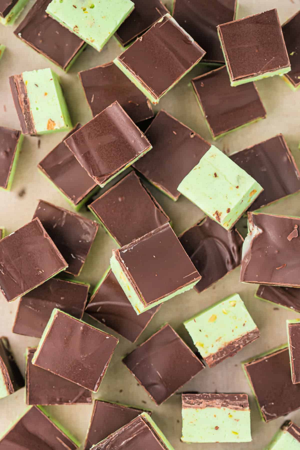 Pistachio fudge with dark chocolate served on a cutting board.