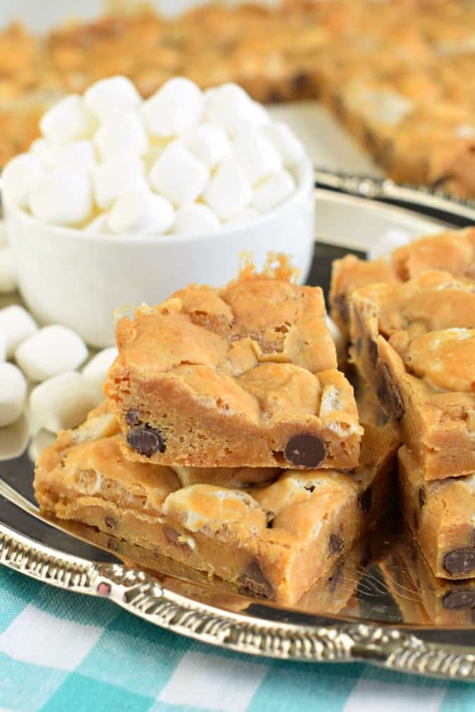 Stack of butterscotch marshmallow bars on silver plate with bowl of mini marshmallows.