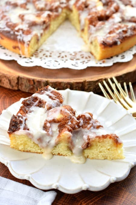 Big slice of cinnamon roll cake topped with cream cheese icing.