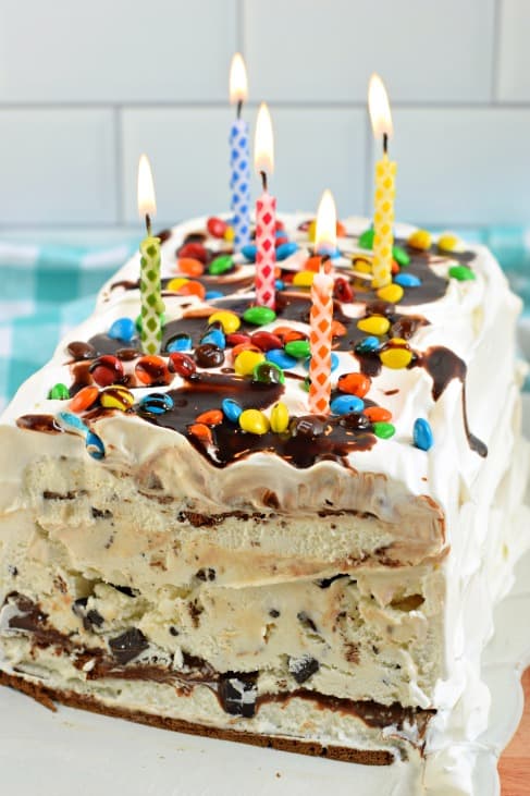 Ice cream cake with layers showing and topped with lit candles.