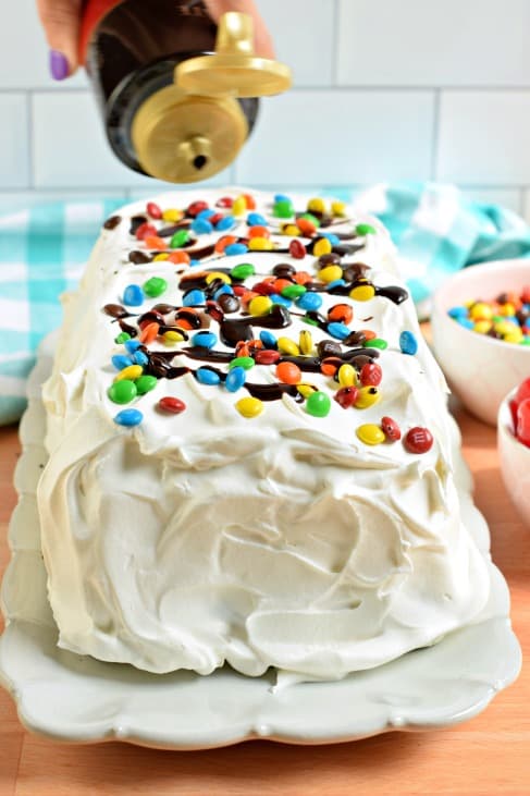 Ice cream cake topped with mini m&m's and chocolate syrup.