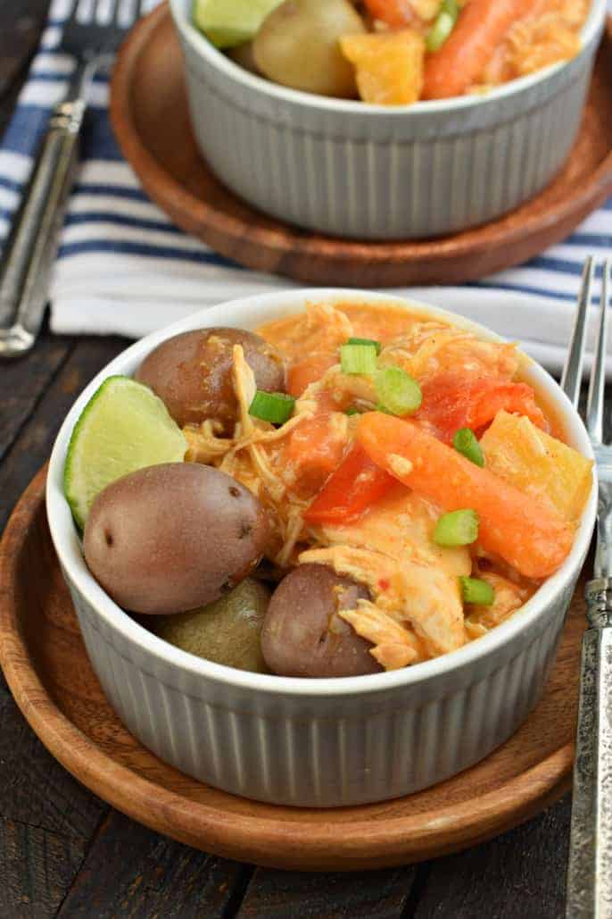 Pineapple chicken curry in a bowl with little potatoes and lime.