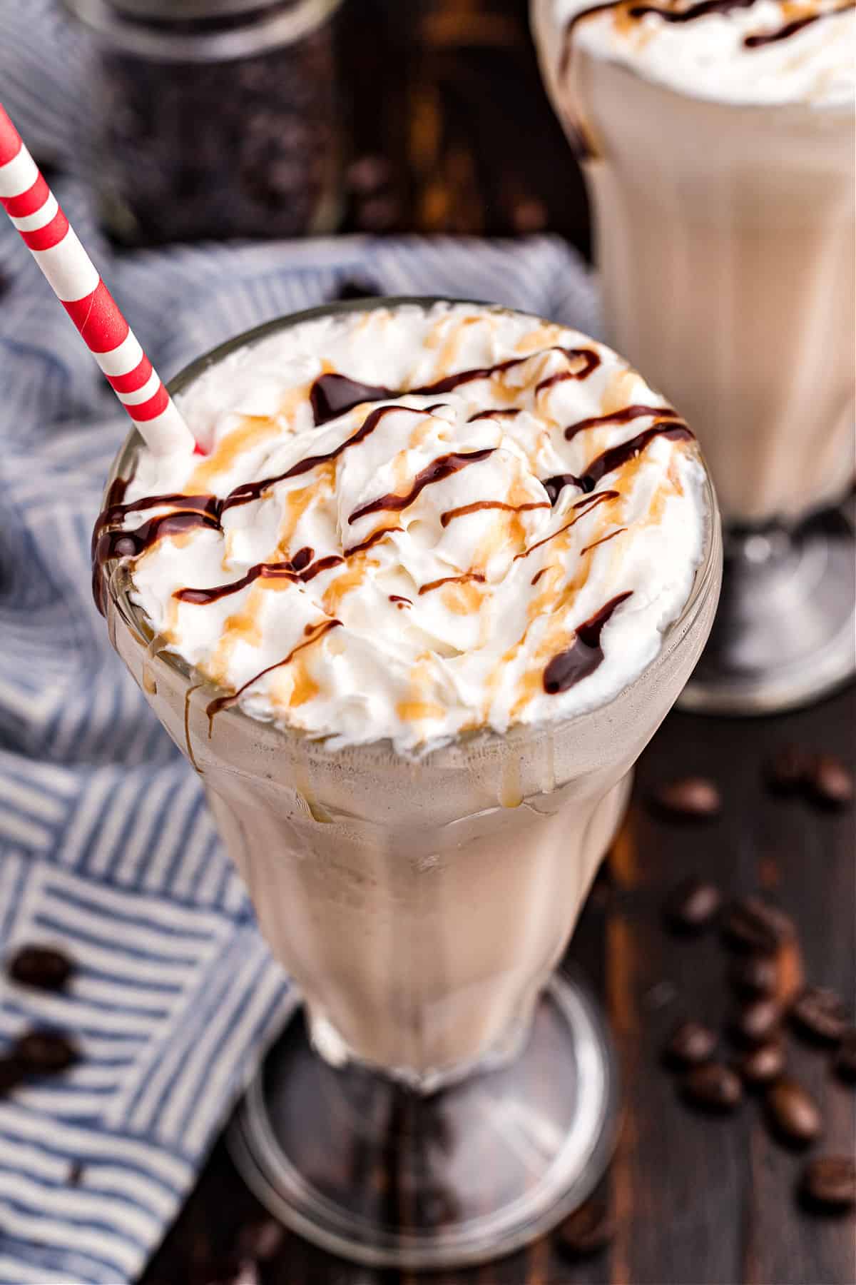 Coffee milkshake in a glass with caramel and chocolate drizzled on top.