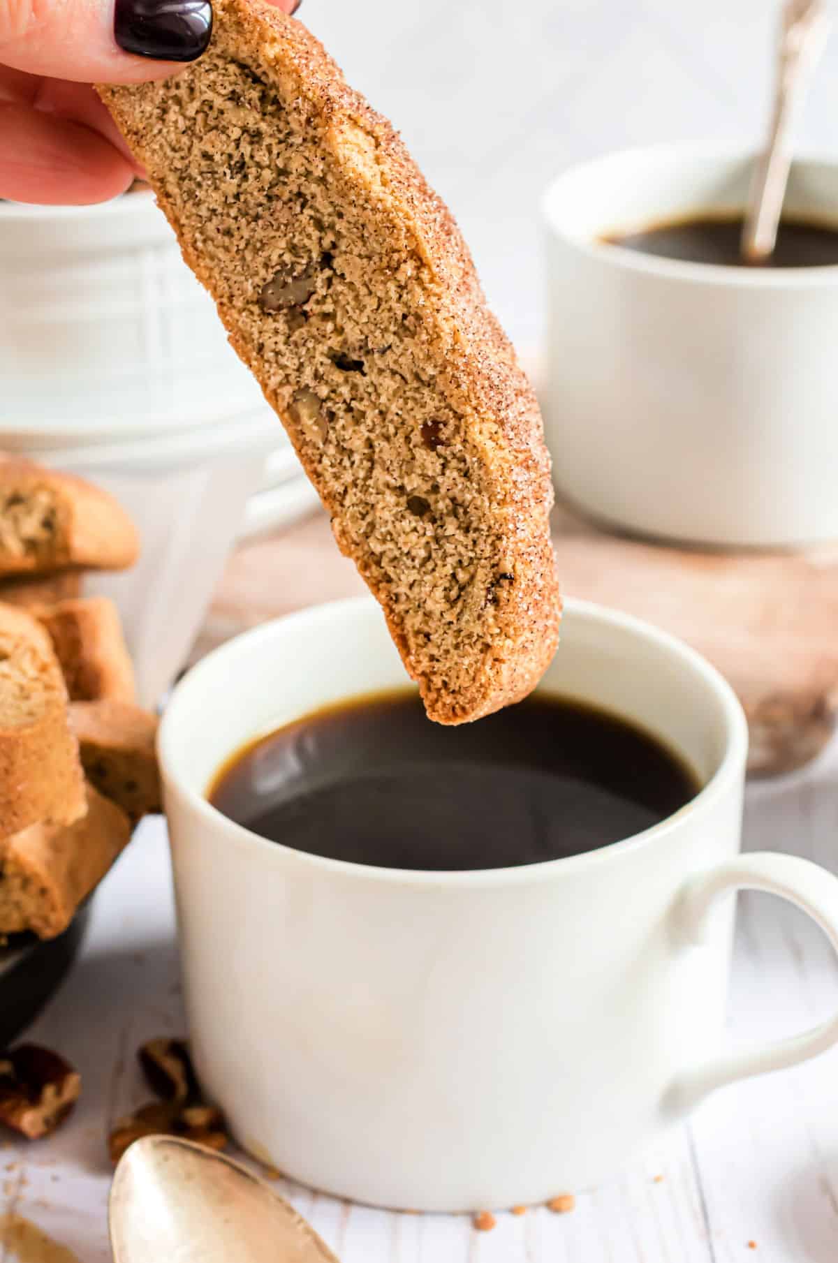 Snickerdoodle biscotti dunked in a mug of black coffee.