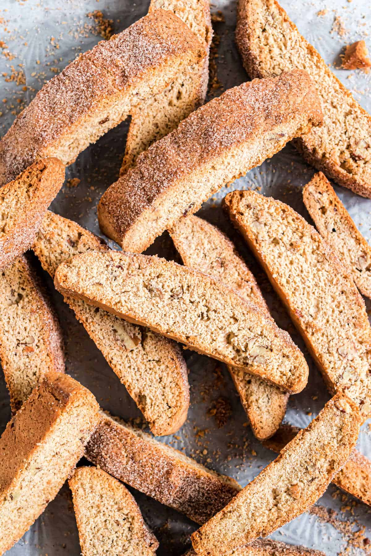 Homemade snickerdoodle biscotti stacked on parchment paper.