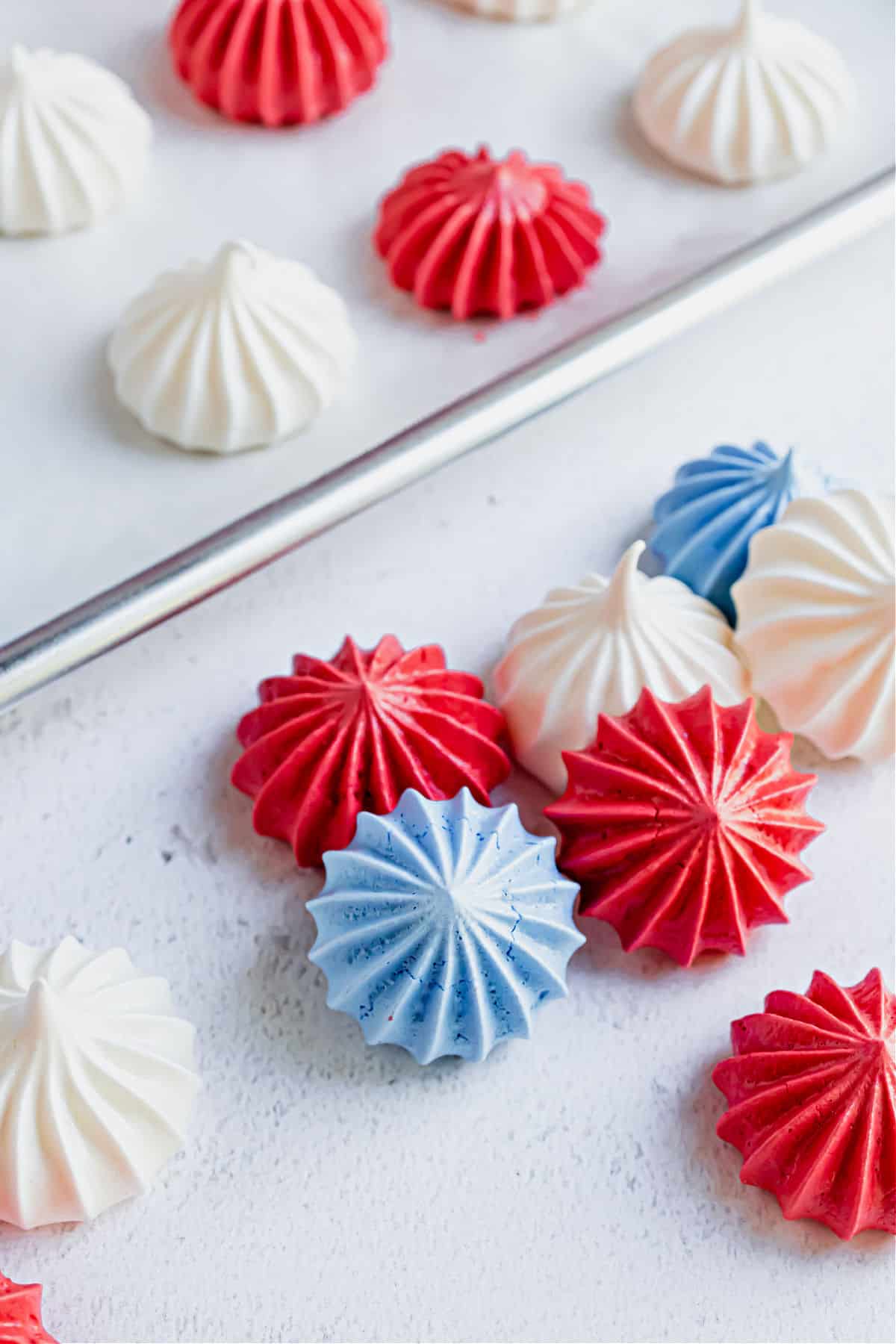 Meringue cookies with a 4th of july theme on baking sheet.