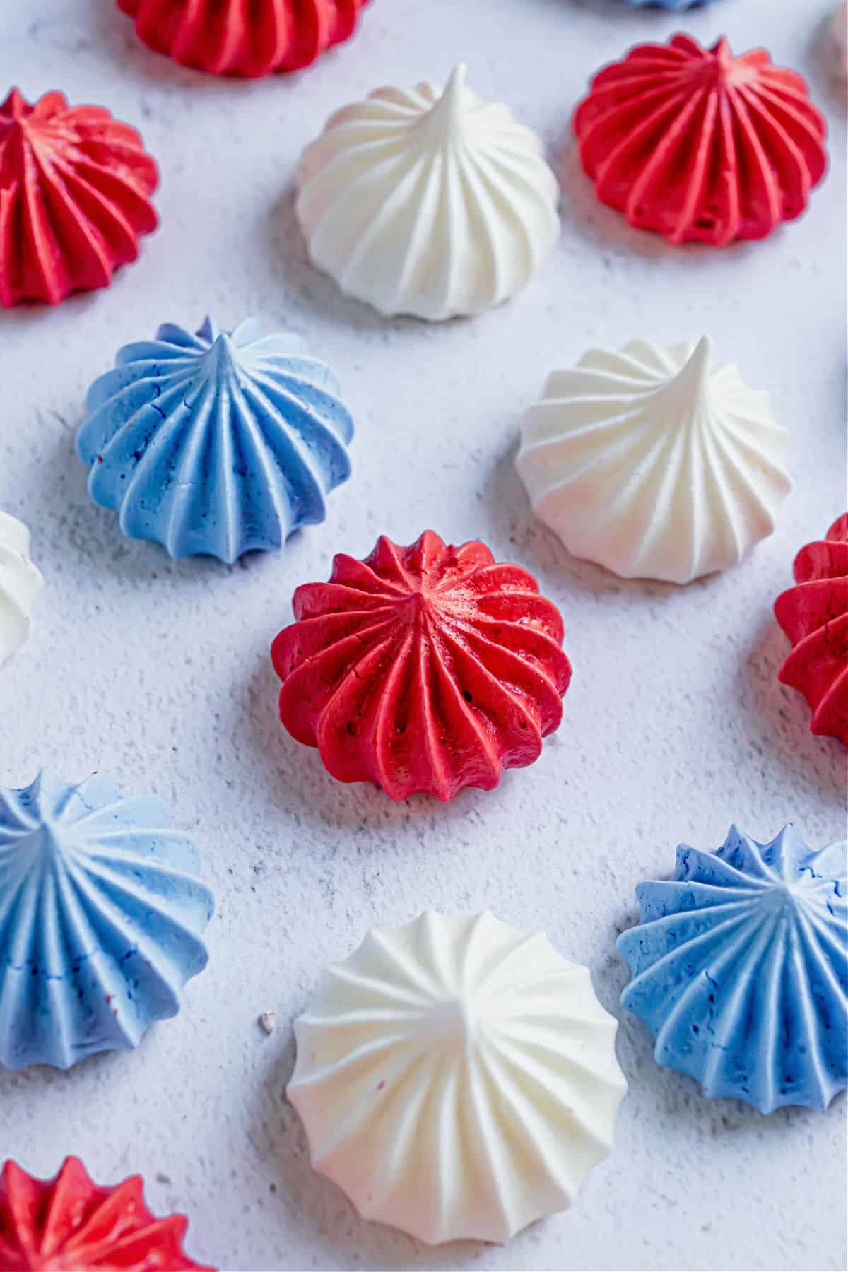 Red white and blue meringue cookies on parchment paper.