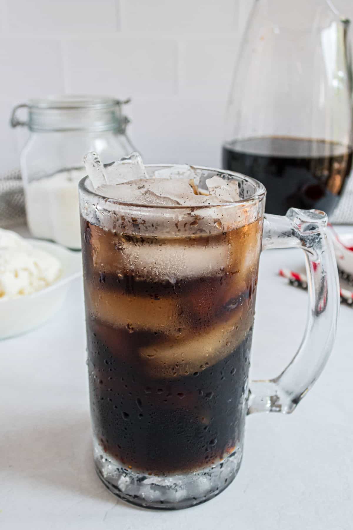 Homemade root beer in a tall glass with ice.