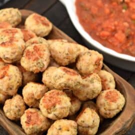 Turkey meatballs in a wooden bowl with bruschetta marinara sauce in the background.