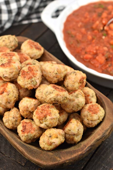 Turkey meatballs in a wooden bowl with bruschetta marinara sauce in the background.