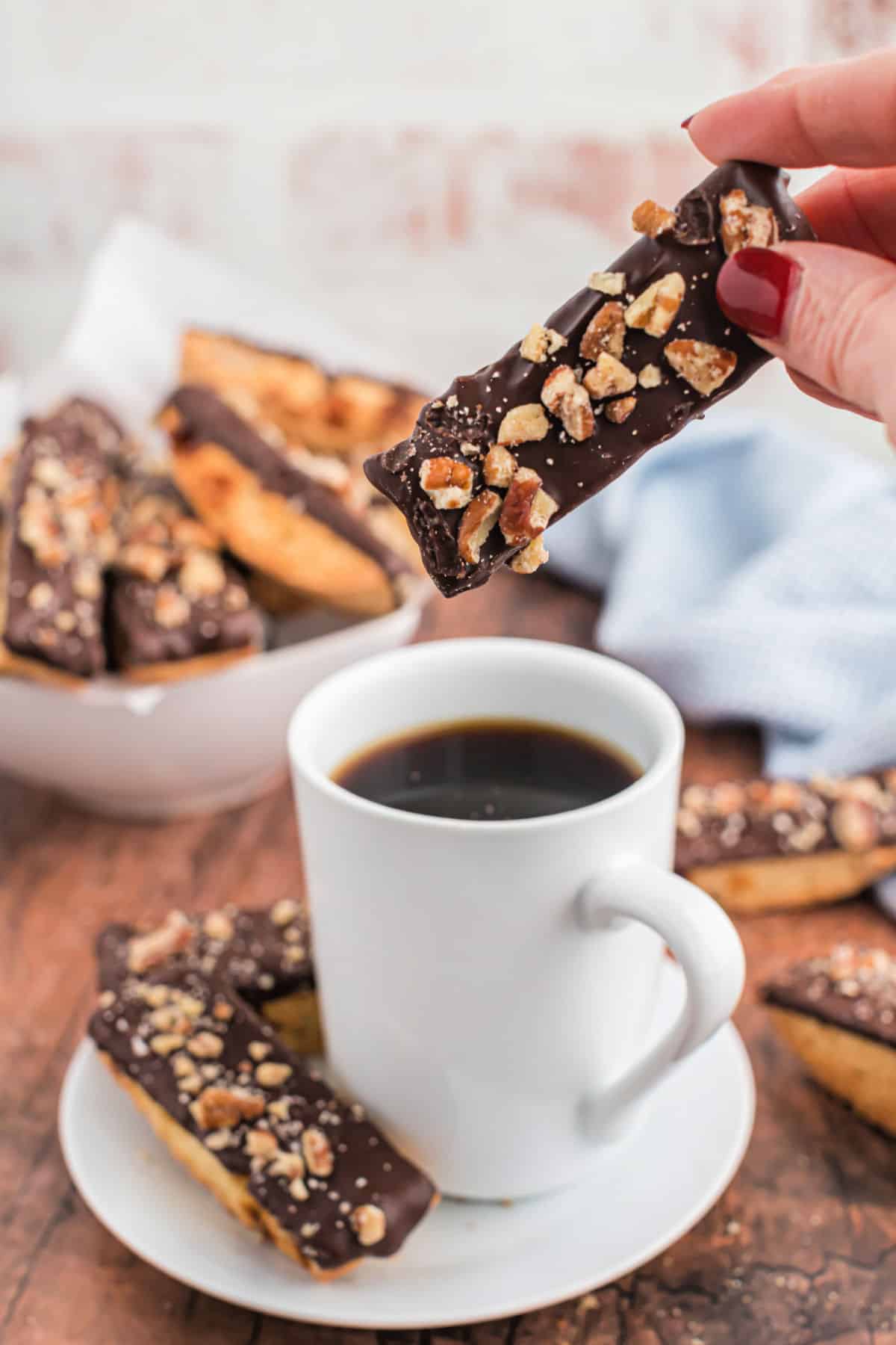 Turtle biscotti being dunked into a mug of coffee.