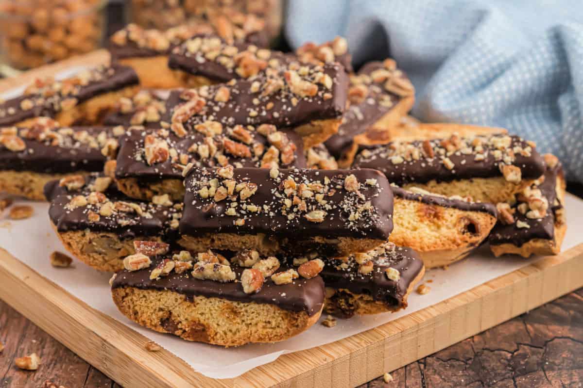 Cutting board topped with biscotti dipped in chocolate.