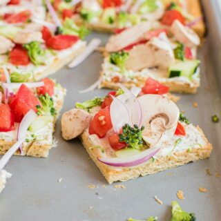 Veggie pizza cut into squares on a metal baking sheet.