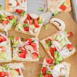 Crescent roll pizza crust topped with dill cream cheese spread and fresh veggies. Cut into squares.