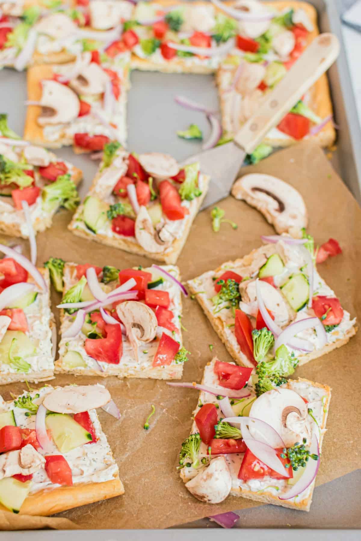 Crescent roll pizza crust topped with dill cream cheese spread and fresh veggies. Cut into squares.