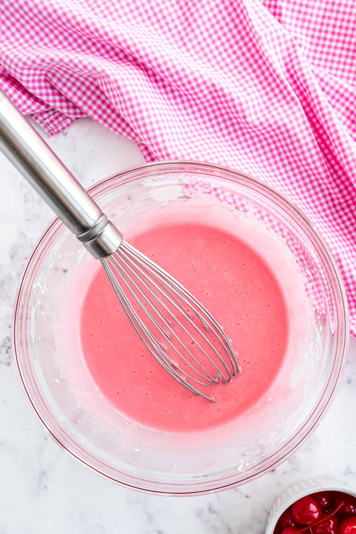 Pink cherry glaze with whisk for pound cake.