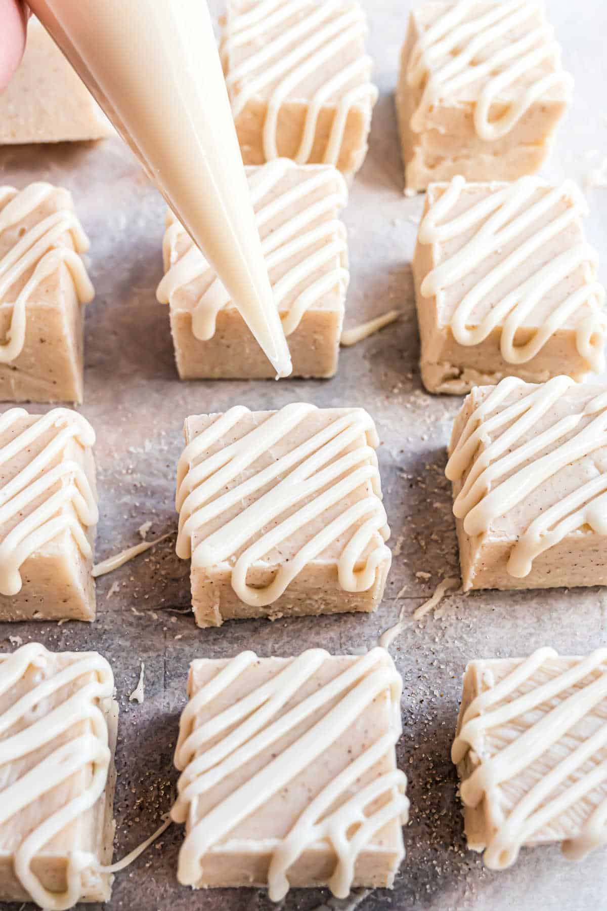 Icing being drizzled on cinnamon roll fudge.