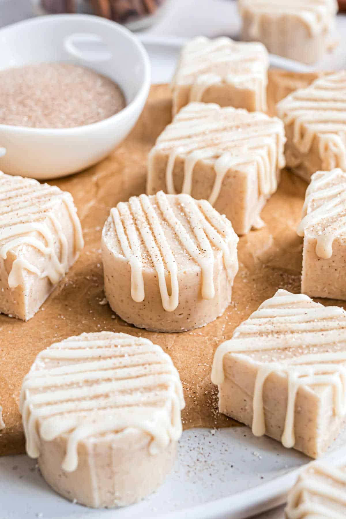 Pieces of fudge drizzled with vanilla icing on parchment paper.