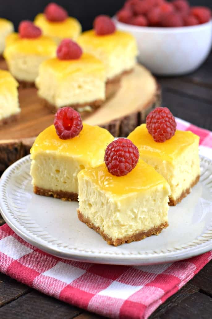 Cheesecake bites topped with lemon curd and fresh raspberries.