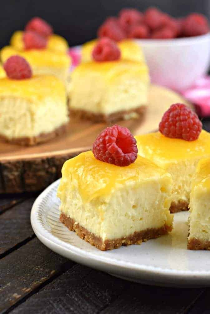 Small squares of cheesecake with lemon curd and raspberry topping.