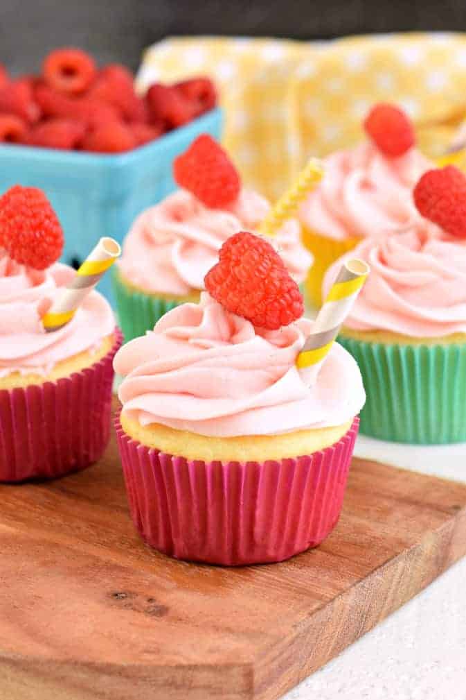 Raspberry Lemonade cupcakes with swirls of frosting and fresh berries.