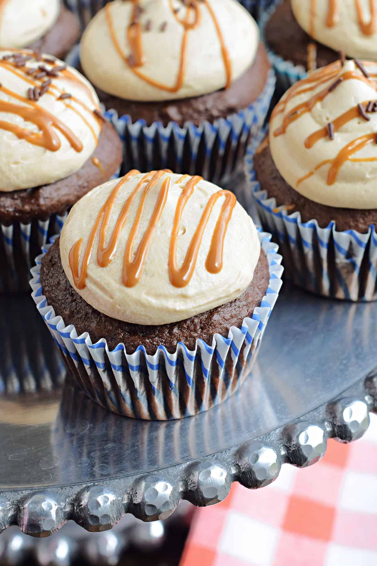 Chocolate cupcake with biscoff frosting on metal cake platter.