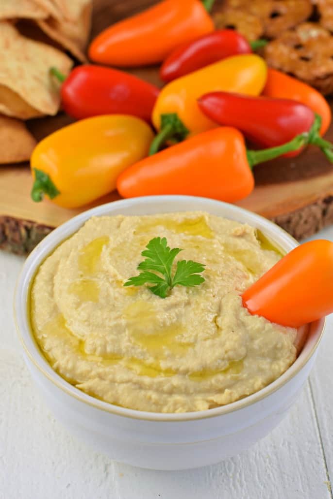 Homemade hummus in a white bowl drizzled with olive oil.