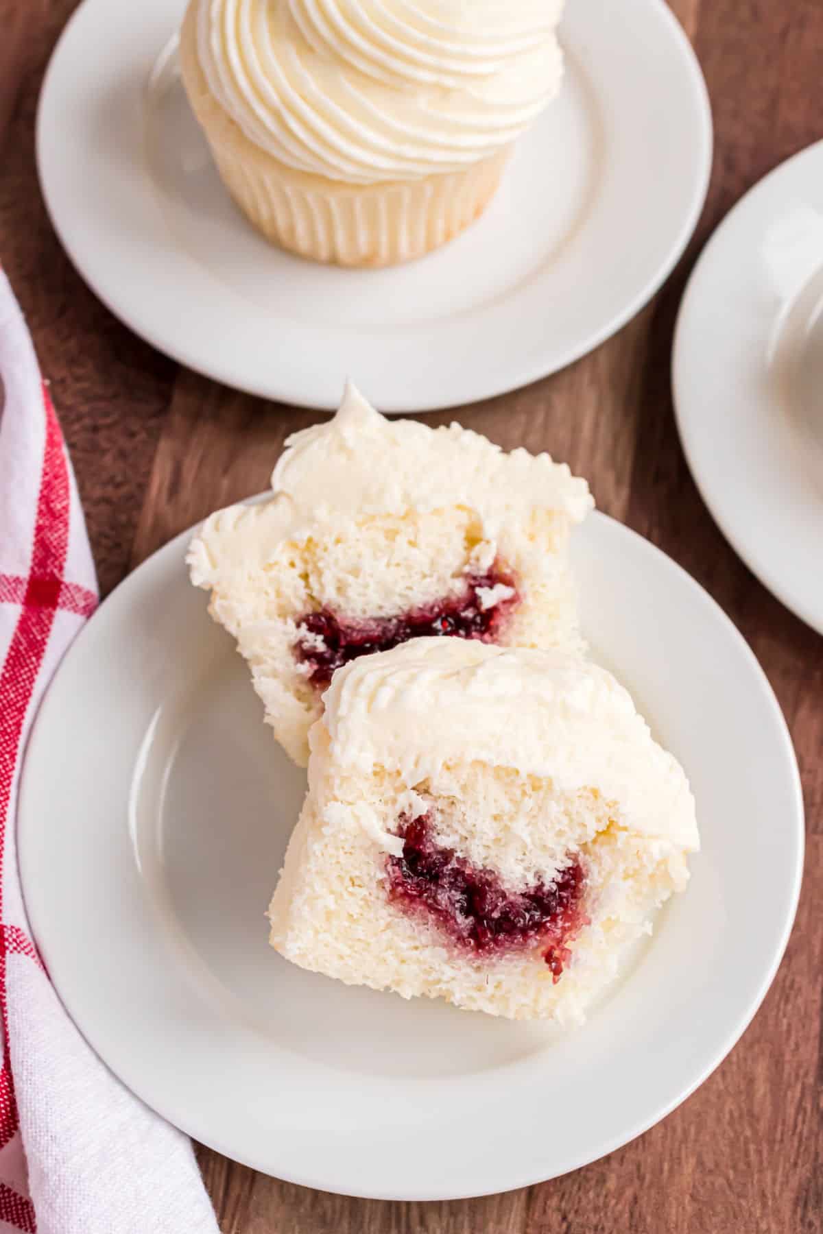 Almond cupcake cut in half with raspberry filling inside.