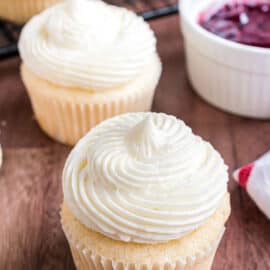Almond cupcakes with big swirls of frosting. Bowl of raspberry presserves for the filling.