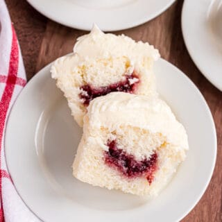 Almond cupcake cut in half with raspberry filing showing.